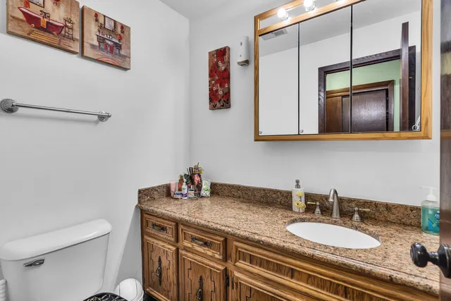 a bathroom with a granite countertop sink a toilet and mirror