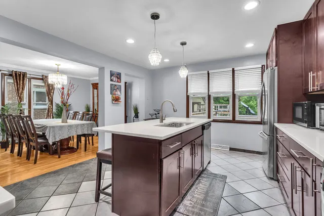 a kitchen with kitchen island granite countertop a stove a sink a dining table and chairs with wooden floor