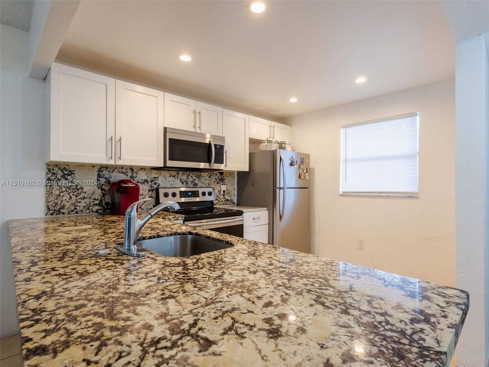 a kitchen with granite countertop a refrigerator and a sink