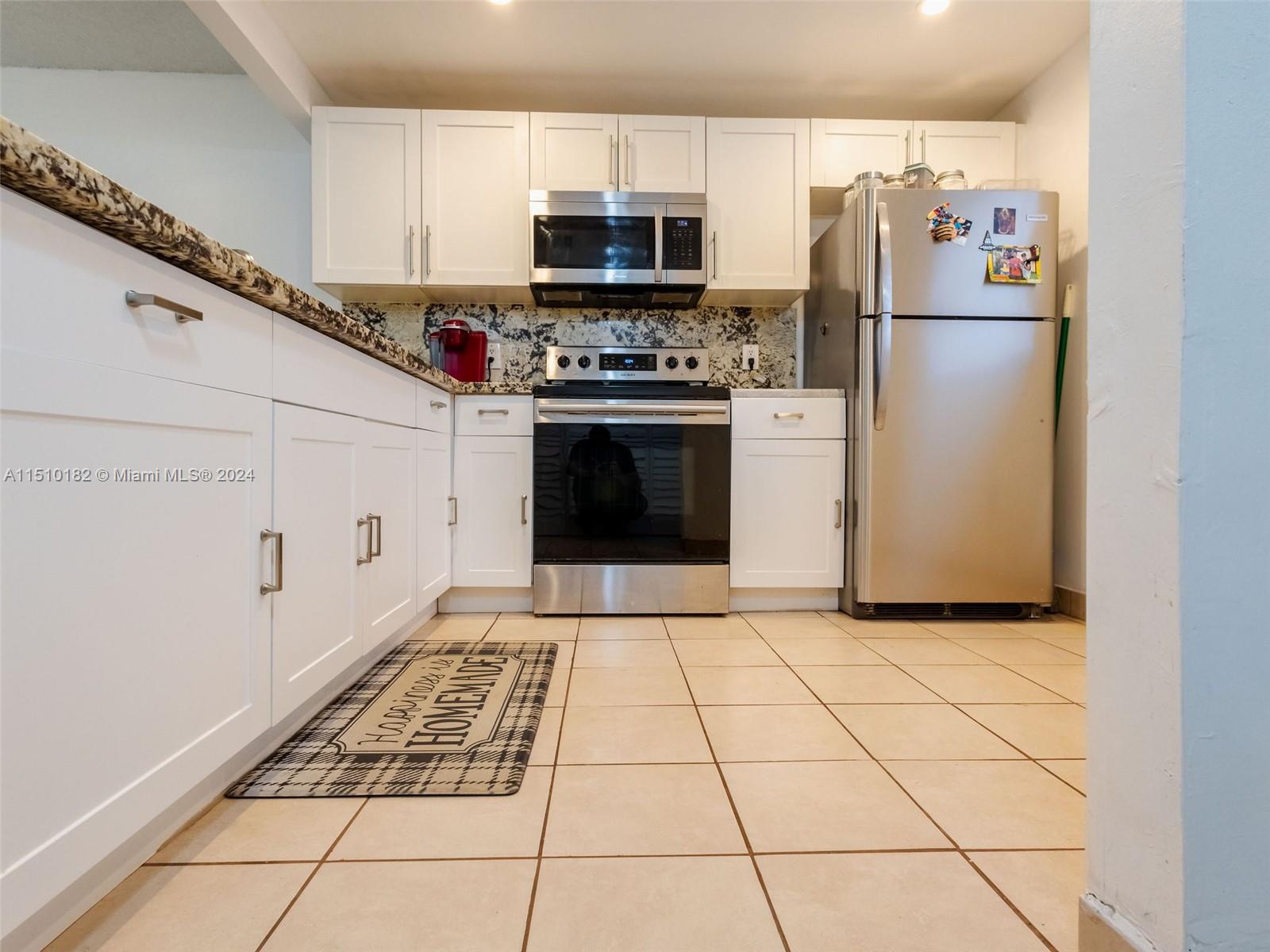 8331 Sands Point Boulevard, Unit C108 Tamarac, FL 33321 - Photo 11 of 46 a kitchen with a stove a refrigerator and a stove top oven
