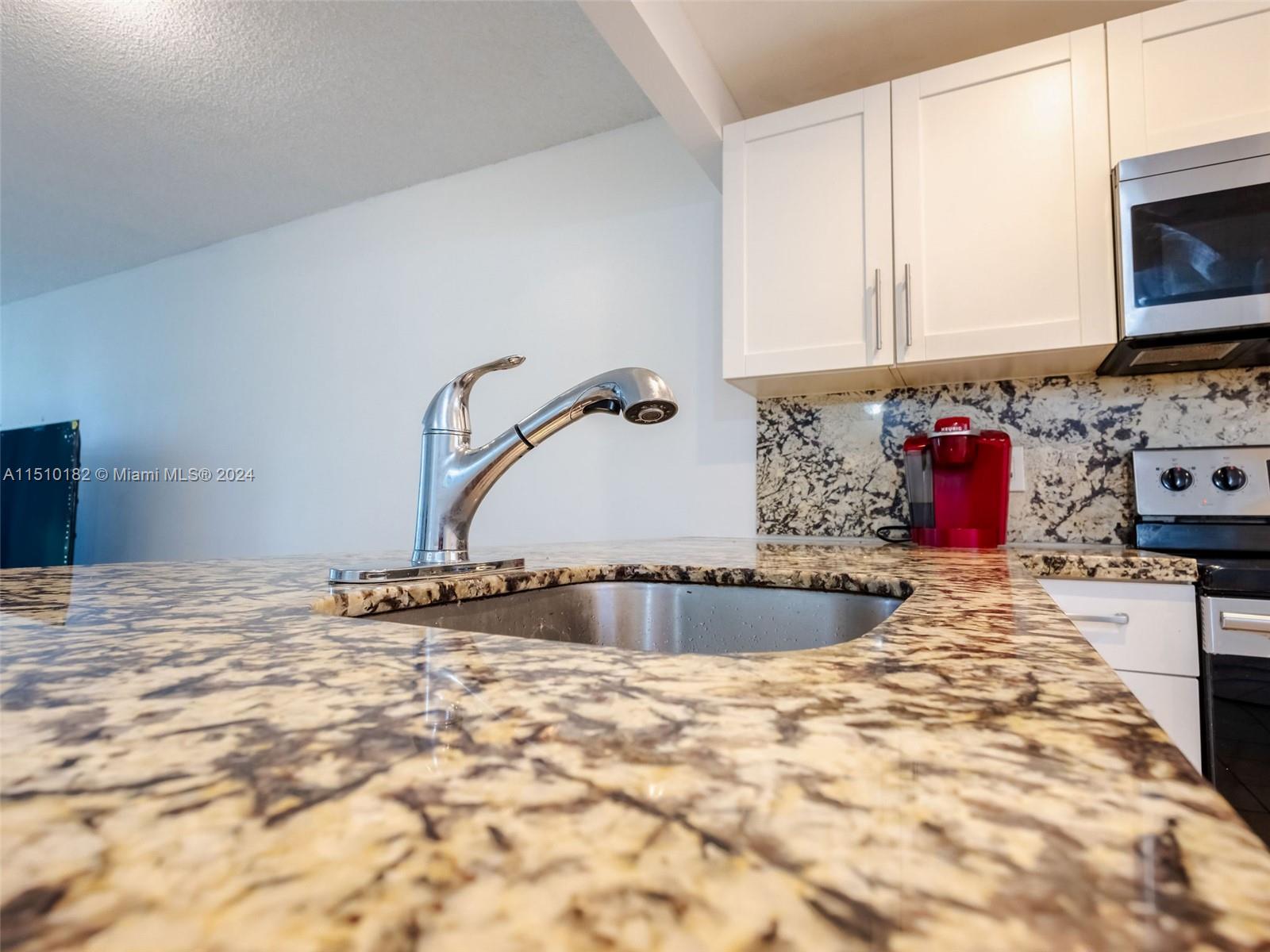 8331 Sands Point Boulevard, Unit C108 Tamarac, FL 33321 - Photo 13 of 46 a kitchen with stainless steel appliances kitchen island granite countertop a sink and a stove