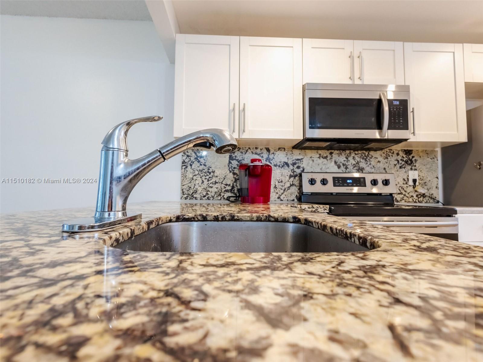8331 Sands Point Boulevard, Unit C108 Tamarac, FL 33321 - Photo 14 of 46 a kitchen with granite countertop a sink and a stove top oven
