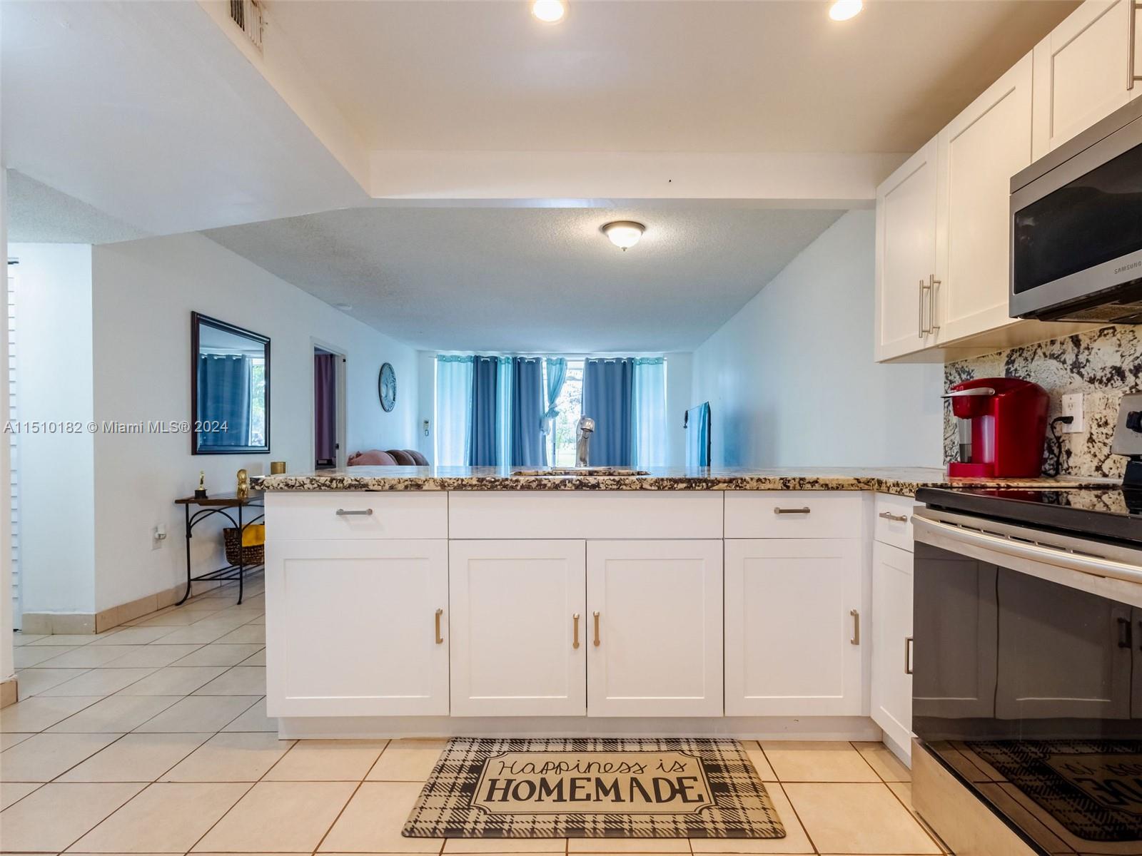 8331 Sands Point Boulevard, Unit C108 Tamarac, FL 33321 - Photo 16 of 46 a kitchen with white cabinets and appliances