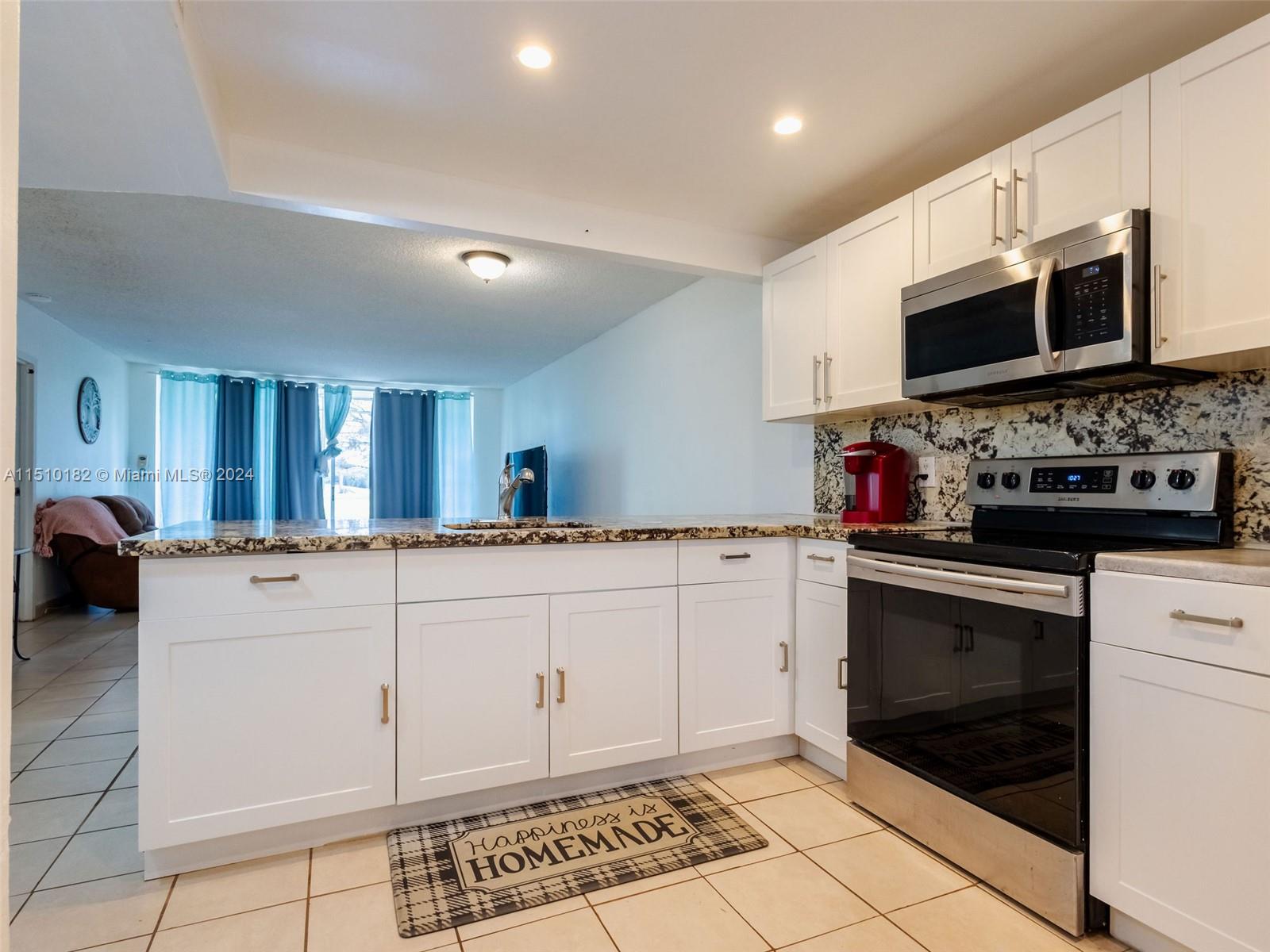 8331 Sands Point Boulevard, Unit C108 Tamarac, FL 33321 - Photo 17 of 46 a kitchen with stainless steel appliances granite countertop a stove a sink and a microwave