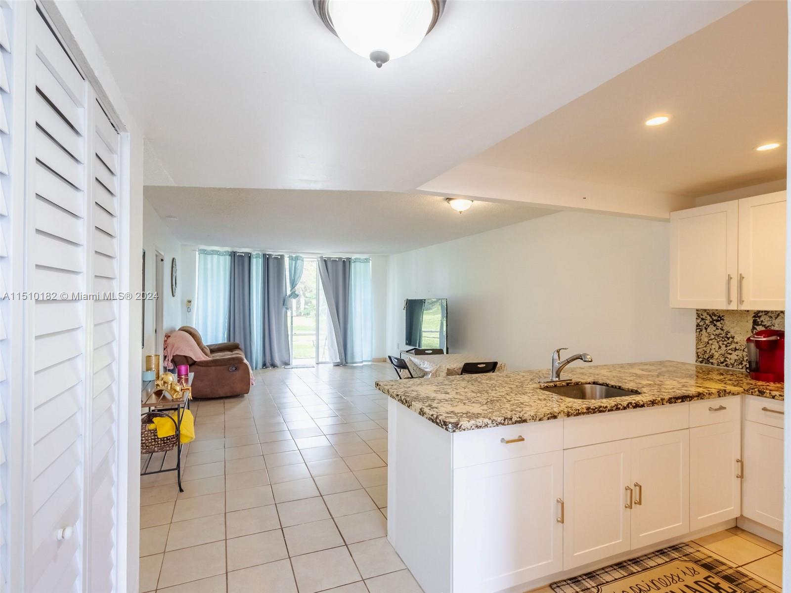 8331 Sands Point Boulevard, Unit C108 Tamarac, FL 33321 - Photo 18 of 46 a kitchen with granite countertop a sink stove and cabinets