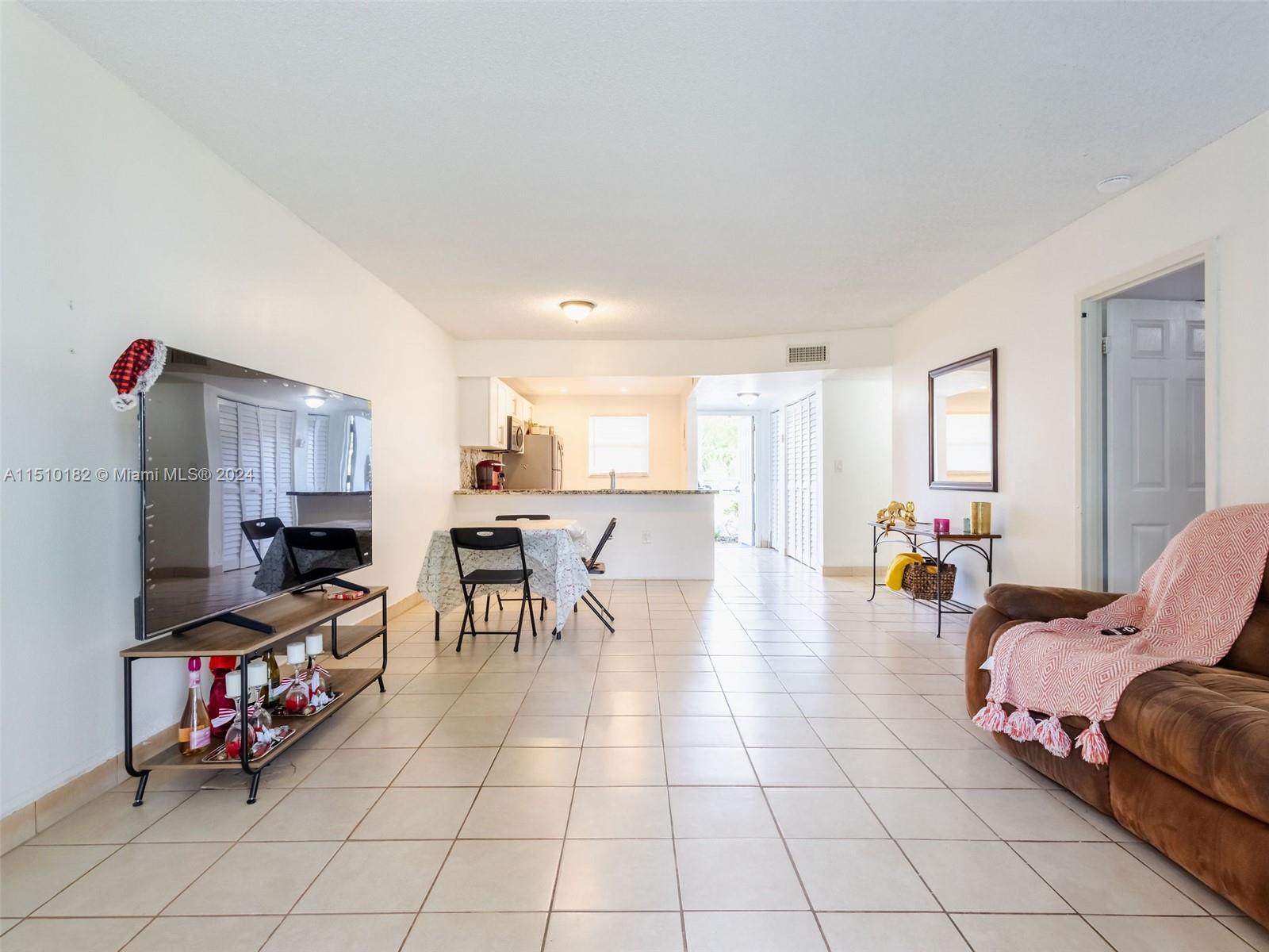 8331 Sands Point Boulevard, Unit C108 Tamarac, FL 33321 - Photo 20 of 46 a living room with lots of furniture and a kitchen view