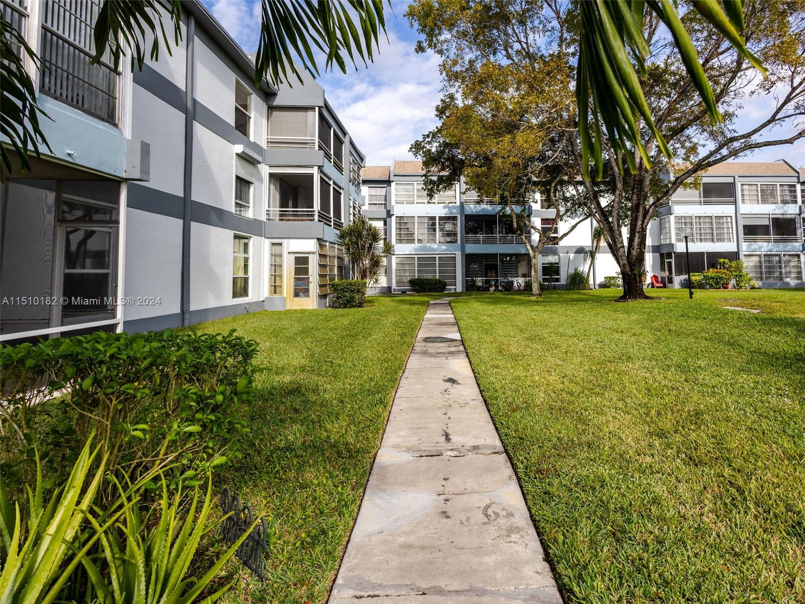 8331 Sands Point Boulevard, Unit C108 Tamarac, FL 33321 - Photo 2 of 46 a front view of a residential apartment building with a yard
