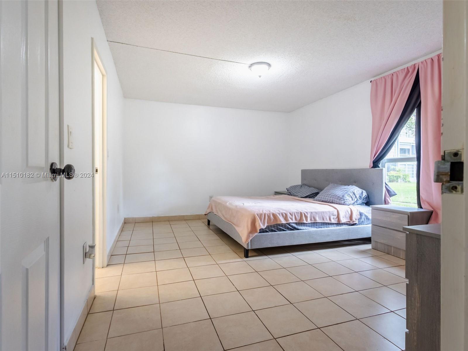 8331 Sands Point Boulevard, Unit C108 Tamarac, FL 33321 - Photo 24 of 46 a spacious bedroom with a bed and a window