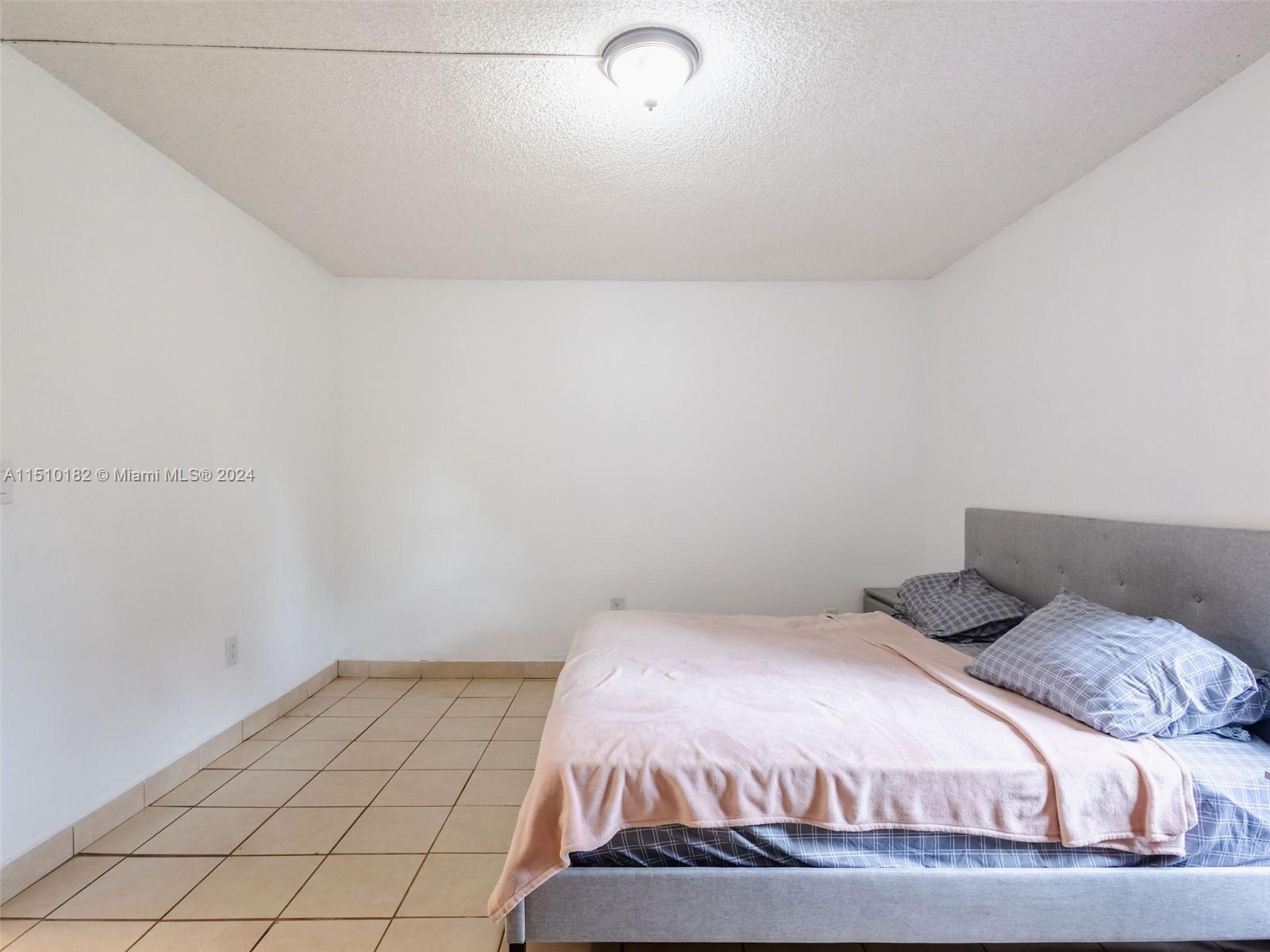 8331 Sands Point Boulevard, Unit C108 Tamarac, FL 33321 - Photo 25 of 46 a bedroom with a bed and a night stand