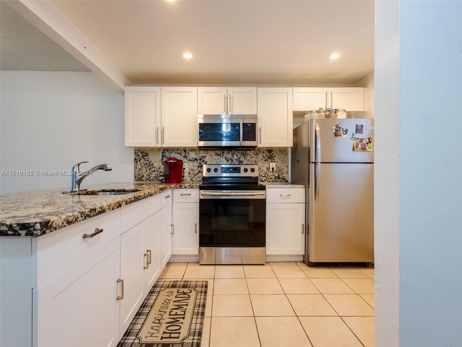 8331 Sands Point Boulevard, Unit C108 Tamarac, FL 33321 - Photo 10 of 46 a kitchen with a stove a sink and a refrigerator