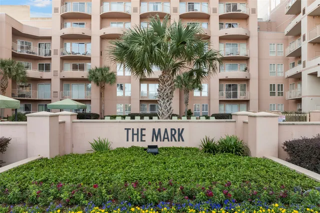 a front view of multi story residential apartment building with yard and sign board