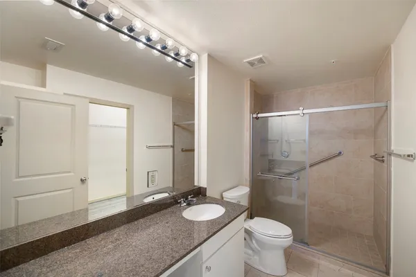 a bathroom with a granite countertop sink toilet and shower