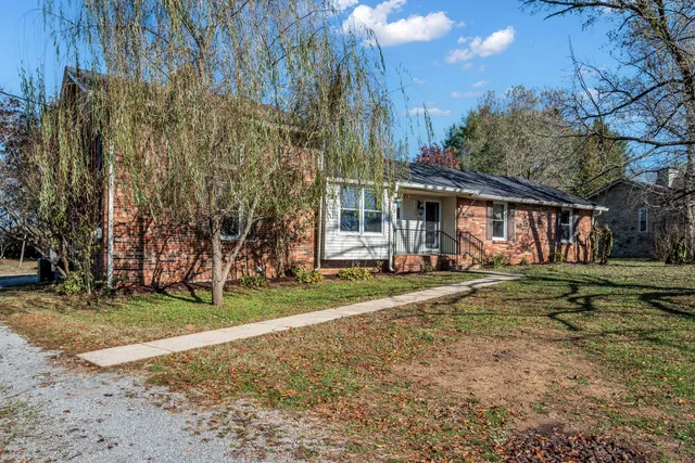 a view of a house with a yard and large trees