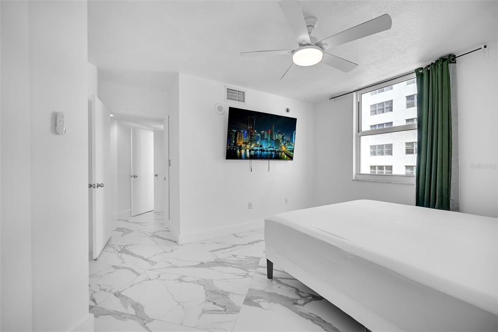 9201 Collins Avenue, Unit 821 Surfside, FL 33154 - Photo 33 of 60 a bedroom with a bed a window and a flat screen tv