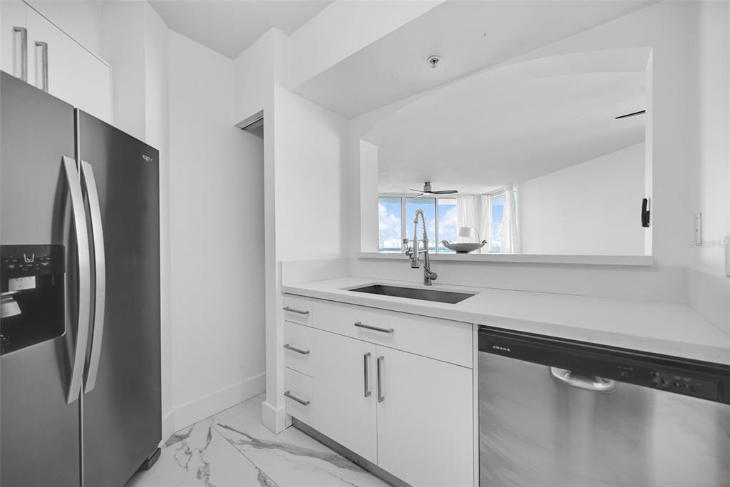9201 Collins Avenue, Unit 821 Surfside, FL 33154 - Photo 48 of 60 a kitchen with white cabinets and stainless steel appliances