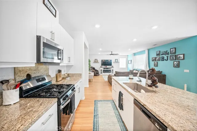 a large kitchen with stainless steel appliances granite countertop a lot of counter space and wooden floor