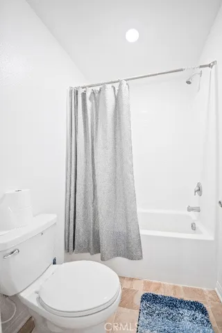 a white toilet sitting next to a bath tub
