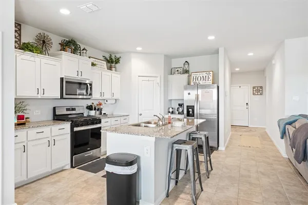 a kitchen with stainless steel appliances granite countertop a stove top oven a sink a dining table and chairs with wooden floor