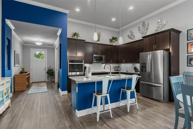a kitchen with stainless steel appliances kitchen island granite countertop a sink stove and refrigerator