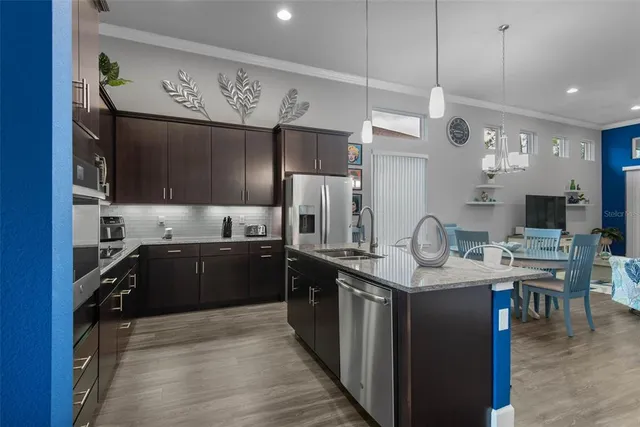 a dining hall with stainless steel appliances granite countertop a sink dishwasher a stove and a dining table with wooden floor