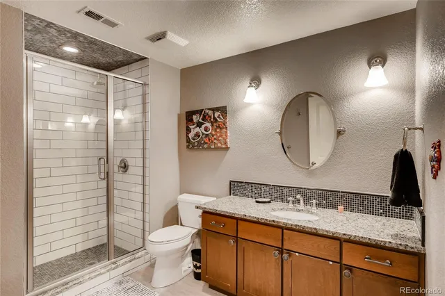 a bathroom with a granite countertop sink mirror vanity and toilet