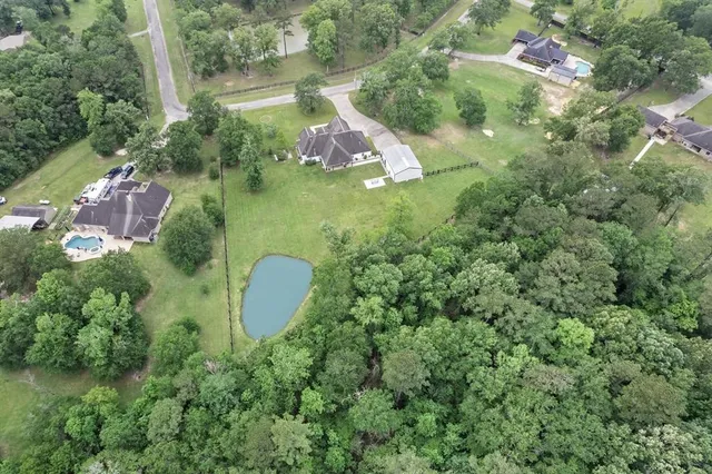 an aerial view of residential house with outdoor space and trees all around