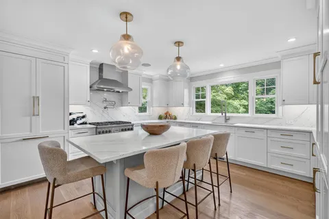 a kitchen with stainless steel appliances a dining table chairs stove and cabinets