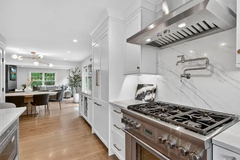 a kitchen with stainless steel appliances granite countertop a stove a sink dishwasher a dining table and chairs with wooden floor