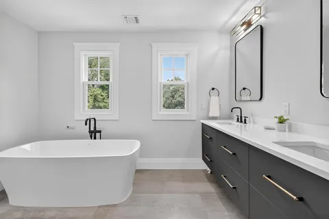 a bathroom with a bathtub sink double vanity and mirror