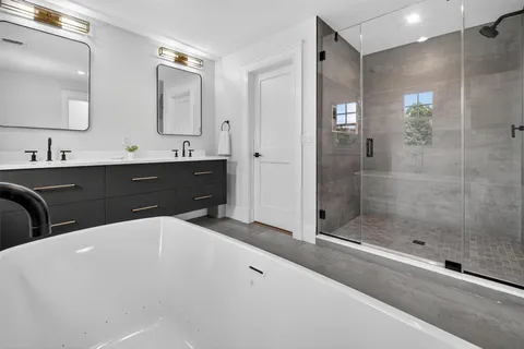 a bathroom with a bathtub and a double vanity sink mirror