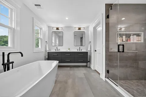 a bathroom with a tub sink shower and mirror