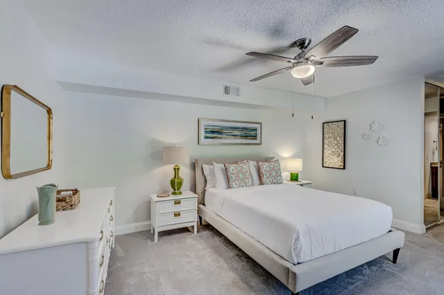 a spacious bedroom with a bed a chandelier and a view of kitchen