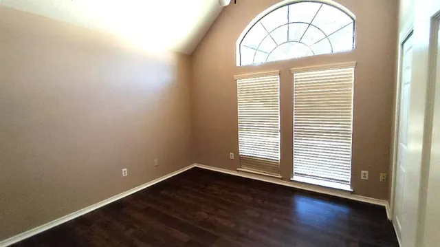an empty room with wooden floor a exposed radiator and a window