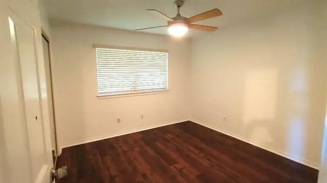 an empty room with a window and ceiling fan