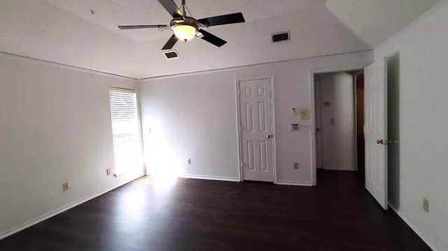 an empty room with wooden floor closet and windows