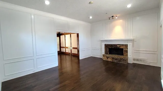 an empty room with wooden floor fireplace and windows