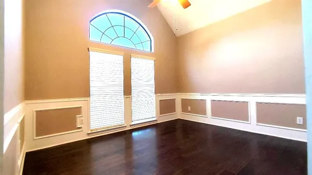 an empty room with wooden floor and windows