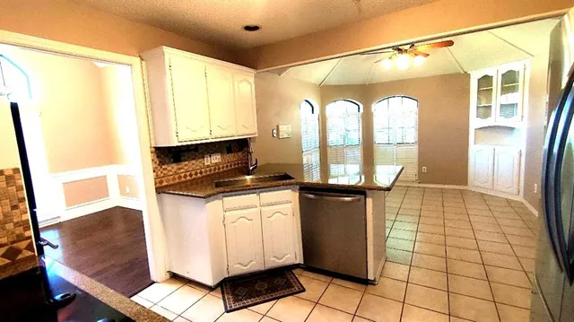 a kitchen with granite countertop a refrigerator a stove and white cabinets with wooden floor