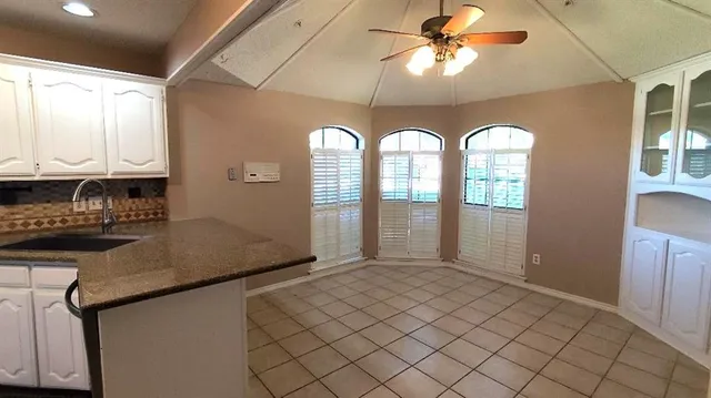 a open kitchen with granite countertop a sink stainless steel appliances cabinets and a large window