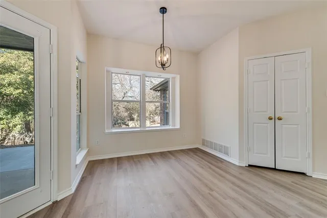 an empty room with wooden floor cabinet and windows