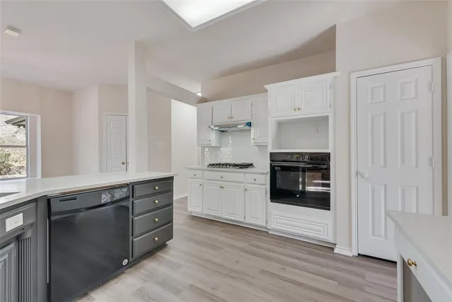 a kitchen with granite countertop white cabinets and appliances