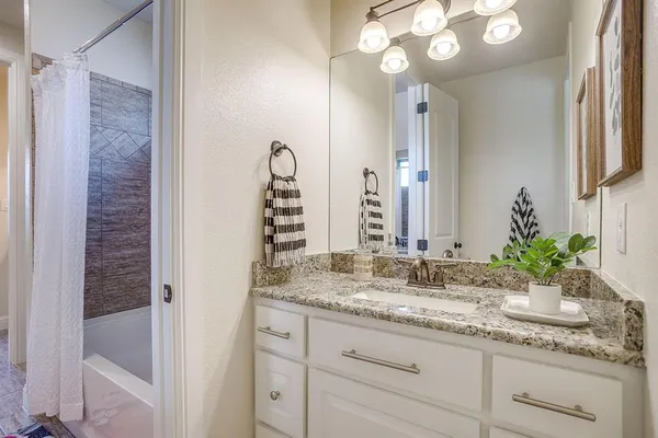 a bathroom with a granite countertop sink a mirror and a shower