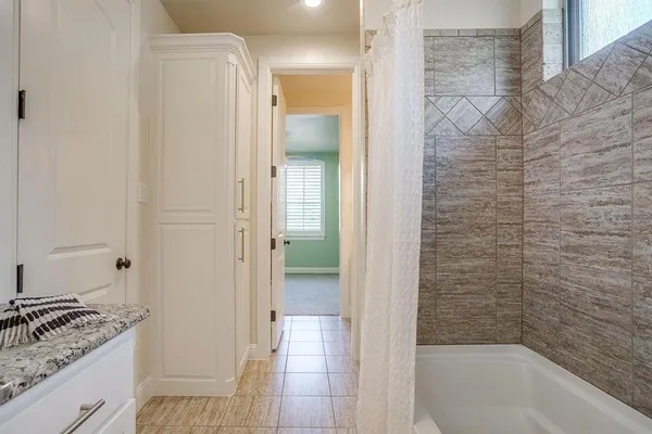 a bathroom with a granite countertop sink a mirror and a bathtub