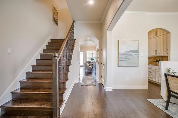 a view of a hallway with wooden floor staircase and a living room