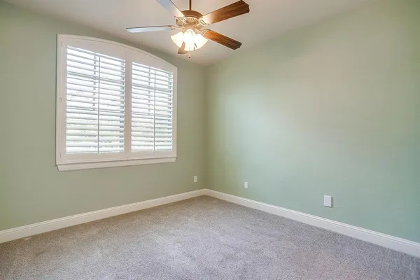 an empty room with a window and a fan