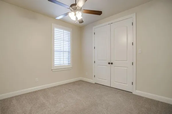 an empty room with chandelier fan and windows