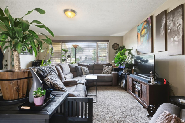 565 East 800 North Logan, UT 84321 - Photo 4 of 27 Carpeted living area featuring a flush-mount ceiling light, a wide window with horizontal blinds, and a built-in media console with storage