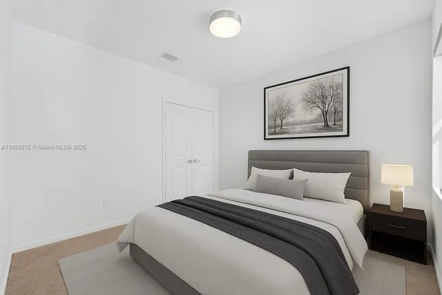 a bedroom with a bed and a lamp on dresser