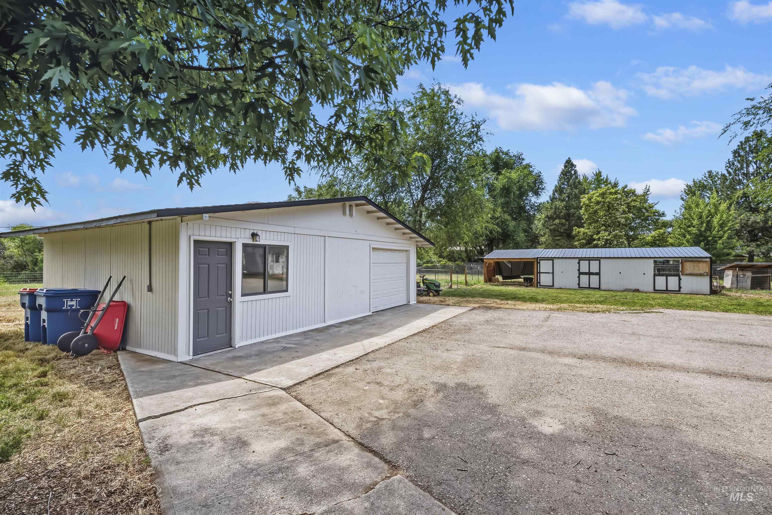 355 East Beacon Light Road Eagle, ID 83616 - Photo 30 of 47 Detached garage with two roll-up doors and a pedestrian entry, alongside a separate outbuilding with multiple bays