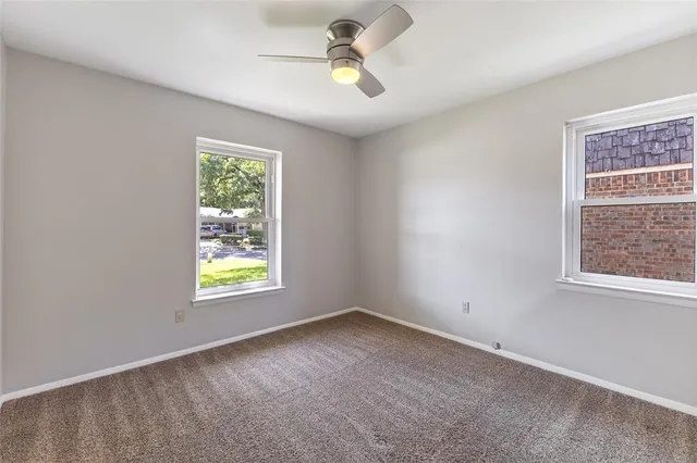 an empty room with window and ceiling fan